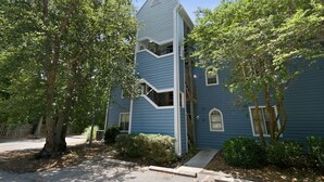 A blue two-story house with a unique architectural design, including a central staircase and a small balcony. - Coastal Condo: Pet friendly/Pool/Mins to UNCW, Downtown & Wrightsville Beach (Wilmington)