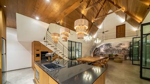 Una cucina moderna con isola centrale, travi in legno a soffitto e illuminazione a sospensione.