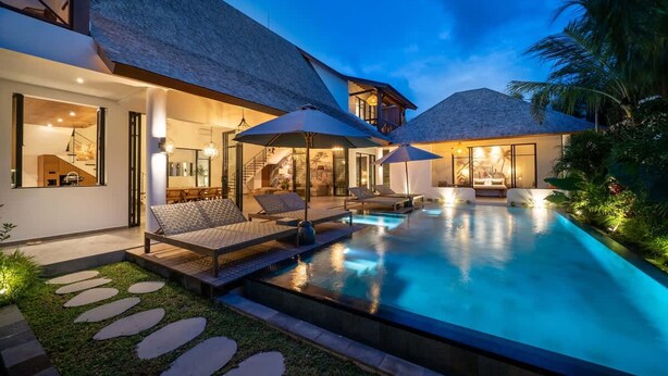 Una casa moderna con piscina, poltrone relax e una scala che conduce a un piano superiore.