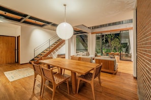 A spacious living area with a wooden dining table, chairs, and a staircase. - Villa Pakuk in Kecamatan Kuta Utara (Kecamatan Kuta Utara)