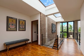 A modern interior with a skylight, wooden flooring, a bench, and artwork on the walls. - Villa Pakuk in Kecamatan Kuta Utara (Kecamatan Kuta Utara)