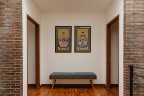 A hallway with a bench, two framed artworks on the wall, and wooden doors. - Villa Pakuk in Kecamatan Kuta Utara (Kecamatan Kuta Utara)