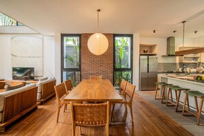 A modern kitchen with a wooden dining table, built-in appliances, and a large window. - Villa Pakuk in Kecamatan Kuta Utara (Kecamatan Kuta Utara)