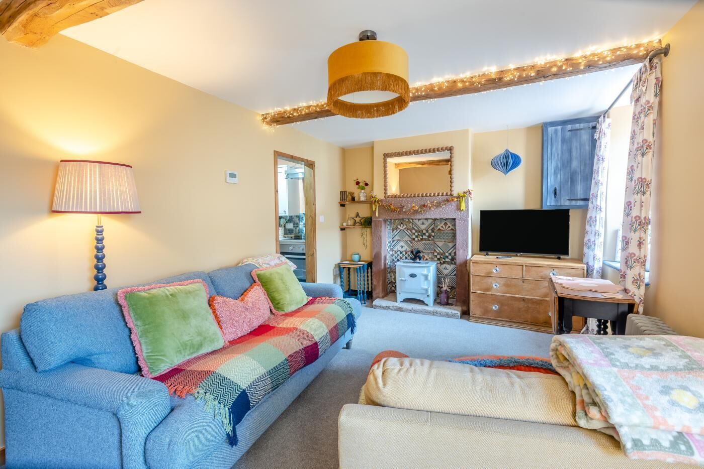 A cozy living room with a sofa, a TV, a fireplace, and a wooden ceiling.