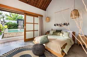 Ein Schlafzimmer mit einem großen Bett, Blick auf einen Swimmingpool und einer Holzbalkendecke.