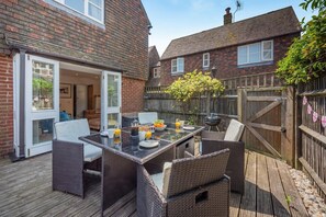 Eine Terrasse mit Frühstückstisch, Korbstühlen und einer Holzterrasse.