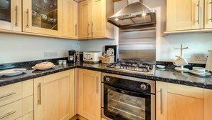A kitchen with wooden cabinets, a gas stove, an oven, and a coffee maker. - 2 Bed in Rye (oc-f44884) (Rye)