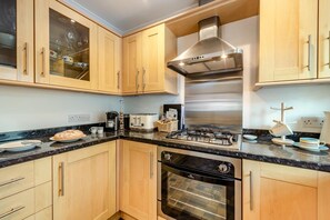 Eine Küche mit Holzschränken, einem Gasherd, einem Backofen und einer Kaffeemaschine.