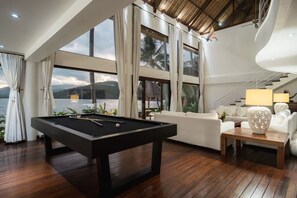 A pool table, a sofa, a lamp, and a view of the sea. - Villa Blanca in Manggis (Manggis)