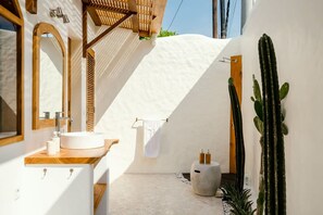 A modern bathroom with a white sink, wooden vanity, and a large cactus. - Canggutopia 2 in Kecamatan Mengwi (Kecamatan Mengwi)
