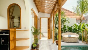 Ein überdachter Außenbereich mit Pool, Holzmöbeln und Kübelpflanzen.
