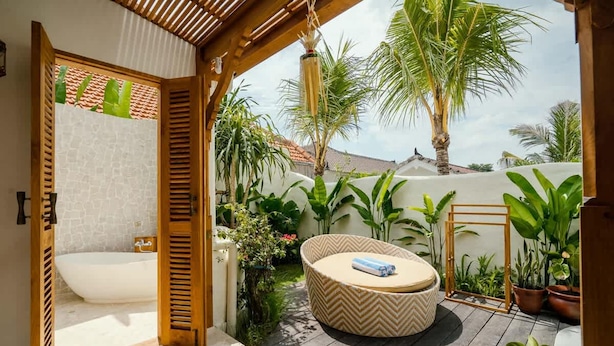 Ein privates Badezimmer im Freien mit Badewanne, einer Holzpergola und üppiger tropischer Bepflanzung.