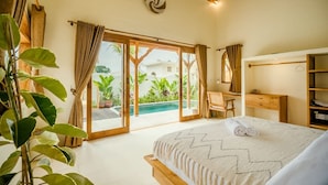 Ein Schlafzimmer mit Bett, Schreibtisch, Stuhl, Blick auf den Pool und einem Balkon.