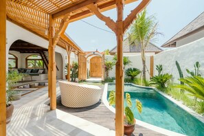 A covered outdoor area with a pool, wooden pergola, and seating. - Canggutopia 4 in Kecamatan Mengwi (Kecamatan Mengwi)