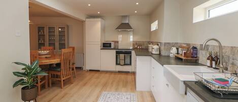 A modern kitchen with a dining area, a built-in microwave, a stove, and a sink with a dish rack.