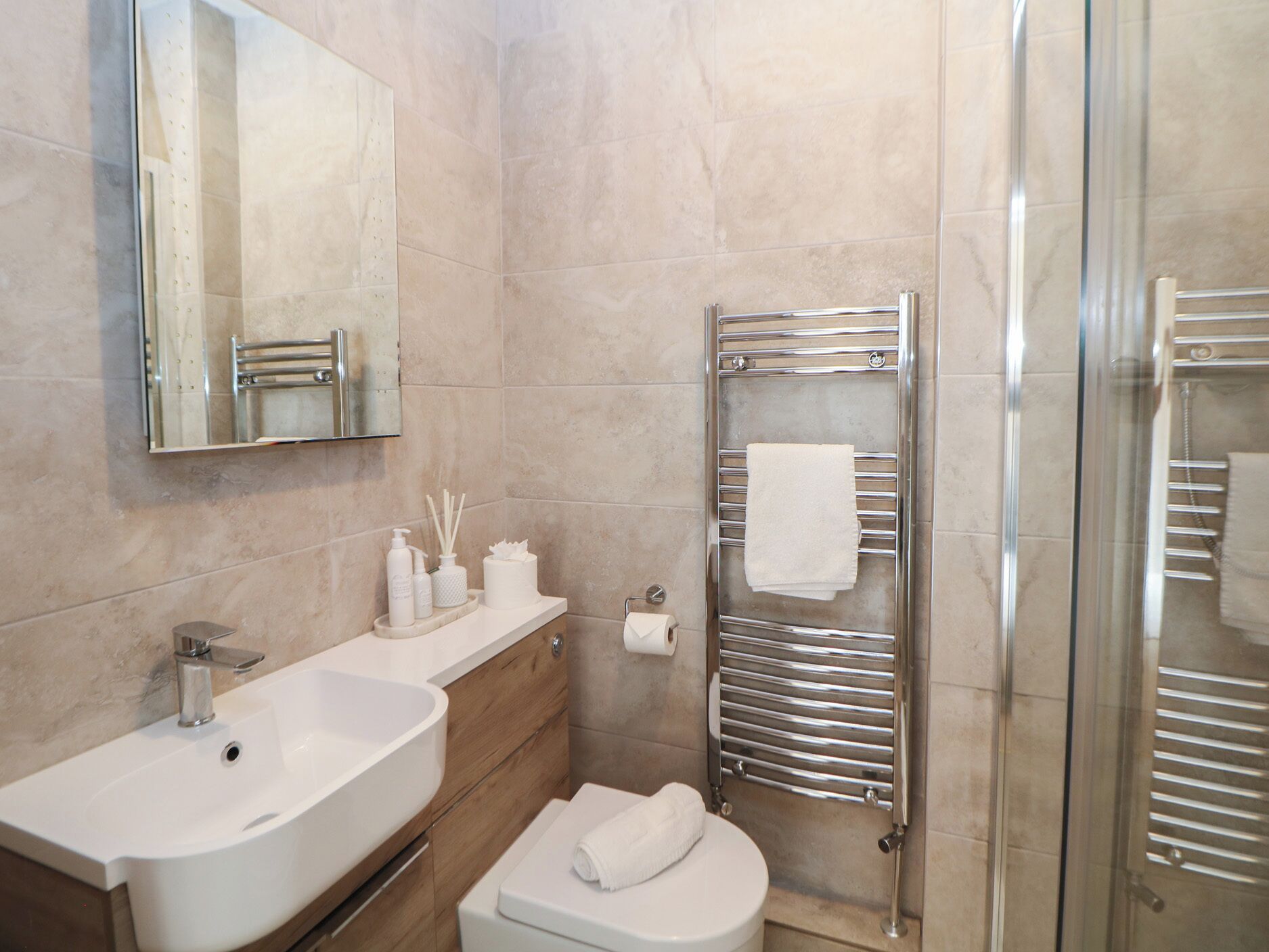 Ein modernes Badezimmer mit Waschbecken, Toilette und einer Duschkabine aus Glas.