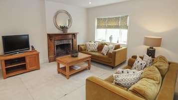 Una sala de estar con chimenea, sofás, televisor y lámpara.