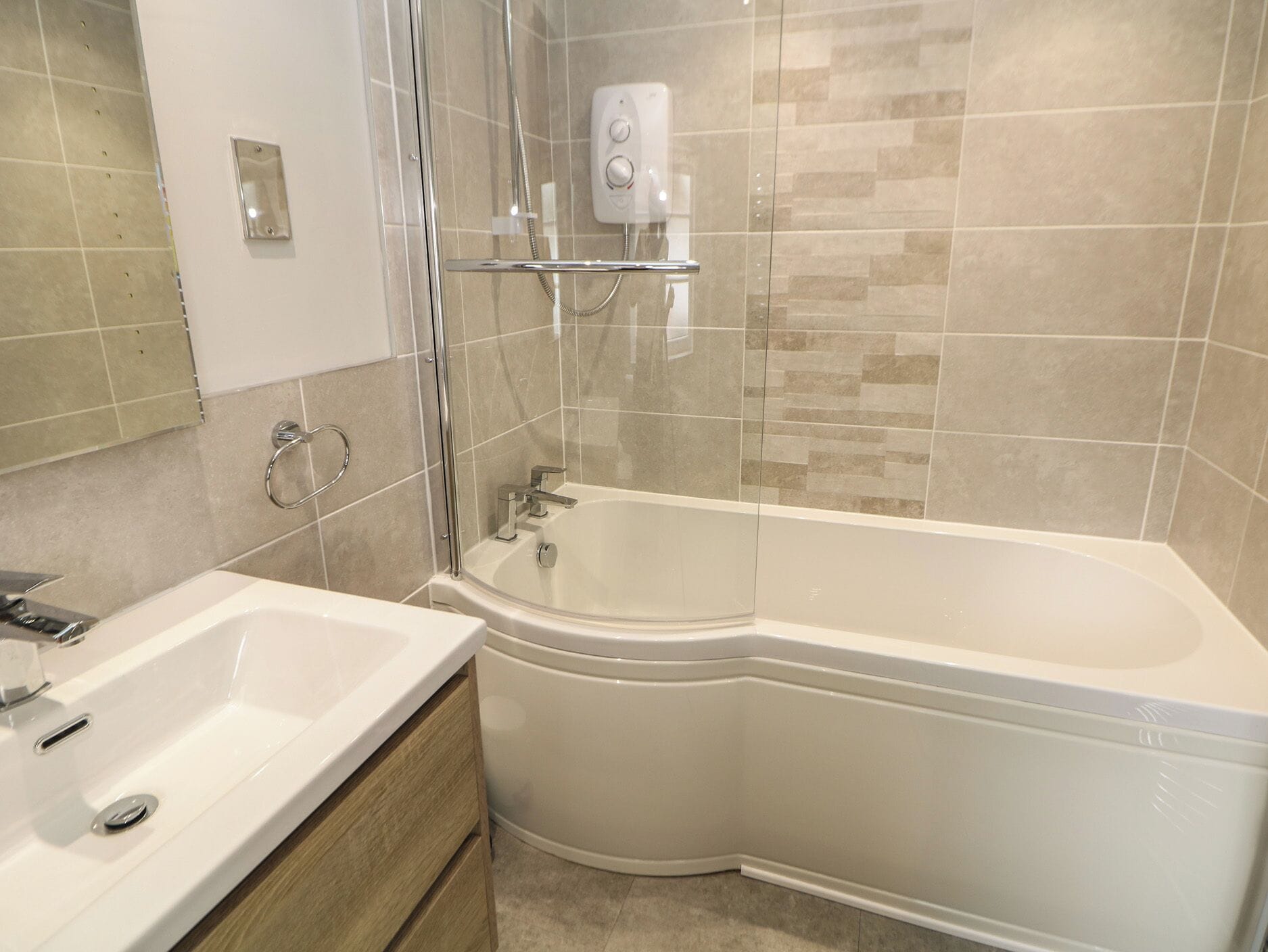 Un baño moderno con bañera en esquina, cabina de ducha con mampara de vidrio y lavamanos blanco.