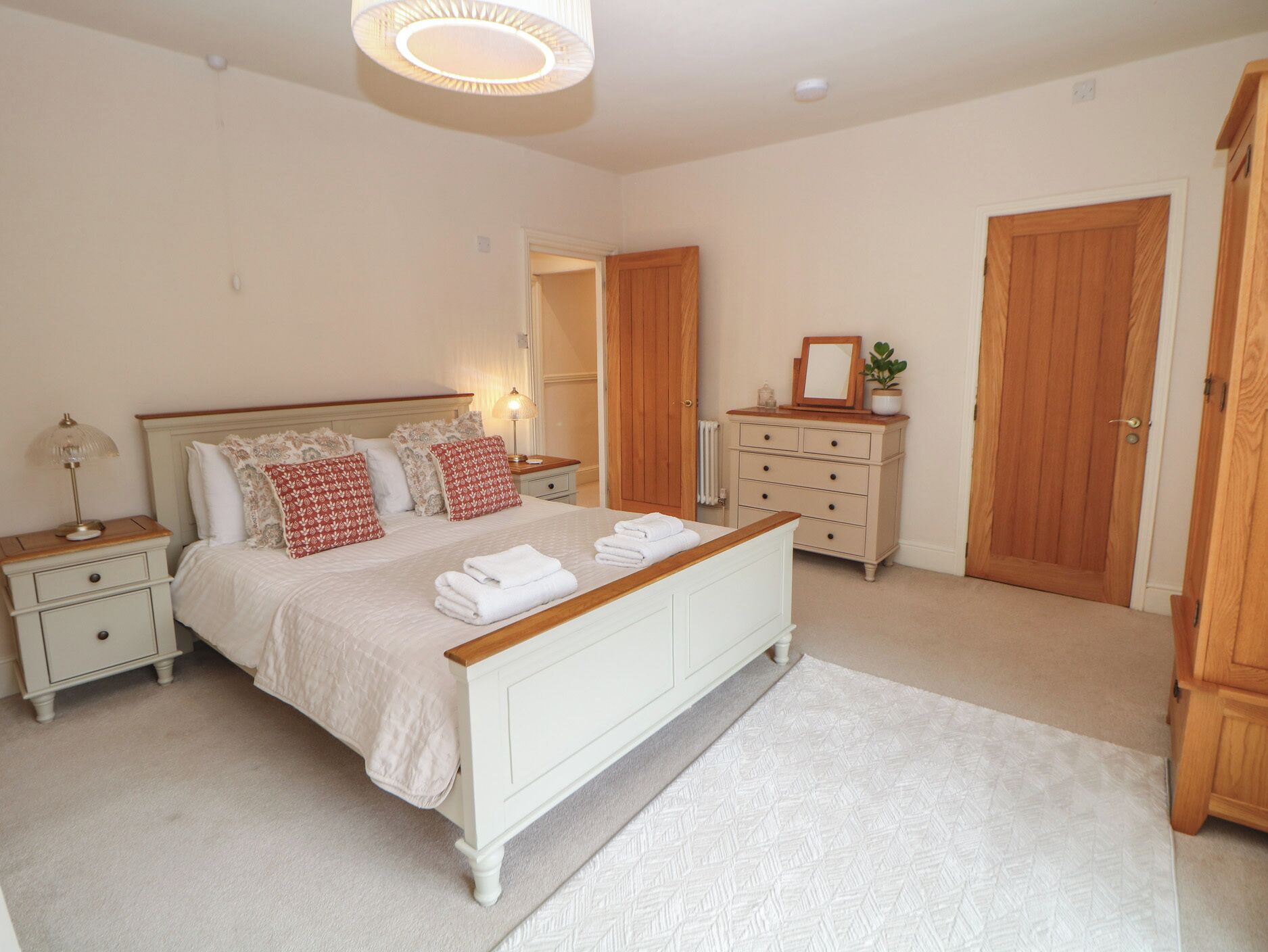 Un dormitorio con cama, mesitas de noche, cómoda y una puerta.