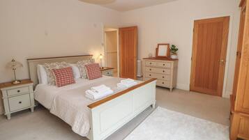 Un dormitorio con cama, mesitas de noche, cómoda y una puerta.