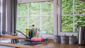 A kitchen with a window, a sink, a dish rack, and kitchen utensils. - Comfortable 3 bed house near Bedgrove park (Aylesbury)
