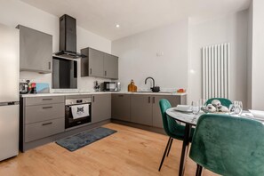 A modern kitchen with grey cabinets, a black range hood, a microwave, and a sink. - 3 Bed in Maryport (oc-l44920) (Maryport)