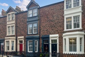 Una hilera de casas adosadas con estilos arquitectónicos variados, incluyendo ventanales salientes y puertas de colores diferentes.