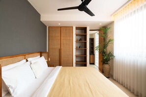 Ein Schlafzimmer mit Bett, Deckenventilator, integriertem Kleiderschrank, Regalen und einem Topfpflanzen.