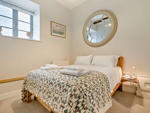 A bedroom with a bed, a round mirror, a window, and a framed picture on the wall. - 2 Bed in St. Austell (oc-43123) (Charlestown)