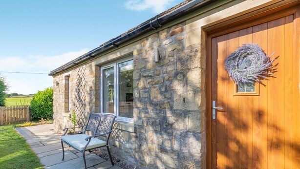 A stone building with a wooden door, a window, and a bench outside. - 1 Bed in Rathmell (oc-w44883) (Gisburn Forest)