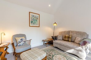 Ein Wohnzimmer mit Sofa, Sessel und einem kleinen Tisch mit Lampe.