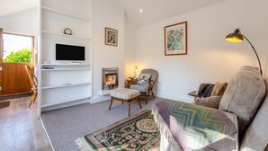 A modern living room with a fireplace, a television mounted on a white wall, a comfortable sofa, and a patterned rug. - 1 Bed in Rathmell (oc-w44883) (Gisburn Forest)