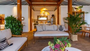 A cozy living area with a sofa, a dining table, and a kitchen in the background. - Villa M2 in Seminyak (Seminyak)