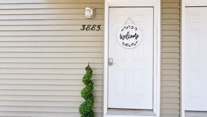 A house with a white door, a 'Welcome' sign, and the number 3885 on the wall.