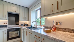 Eine moderne Küche mit Einbauofen, Spüle und Arbeitsplatte mit einer Schachtel und einer Flasche.