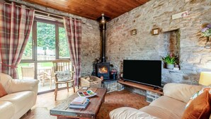 Een gezellige woonkamer met een stenen openhaard, een televisie en comfortabele zitmogelijkheden.