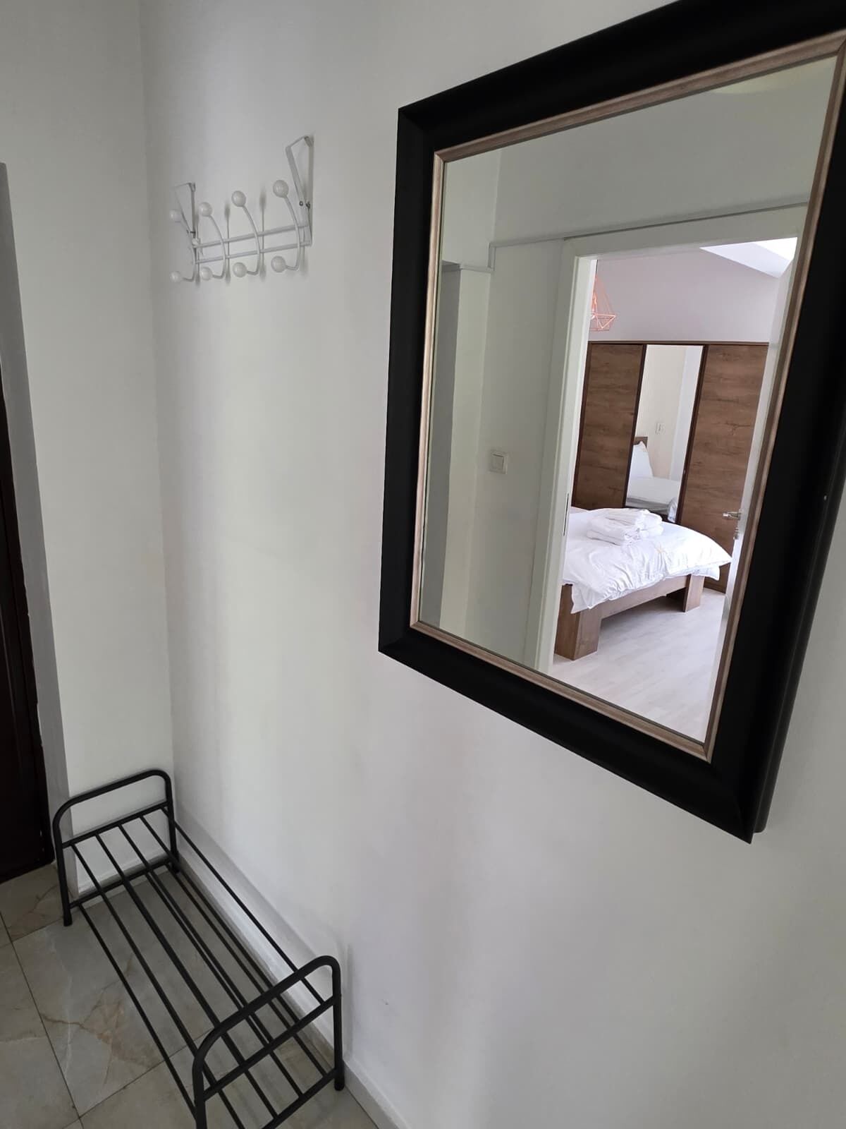 A bedroom with a large mirror, a bed, and a small metal shelf.