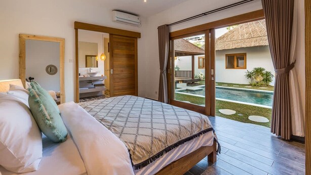 Un dormitorio con cama, espejo, equipo de aire acondicionado y vista a una piscina al aire libre.