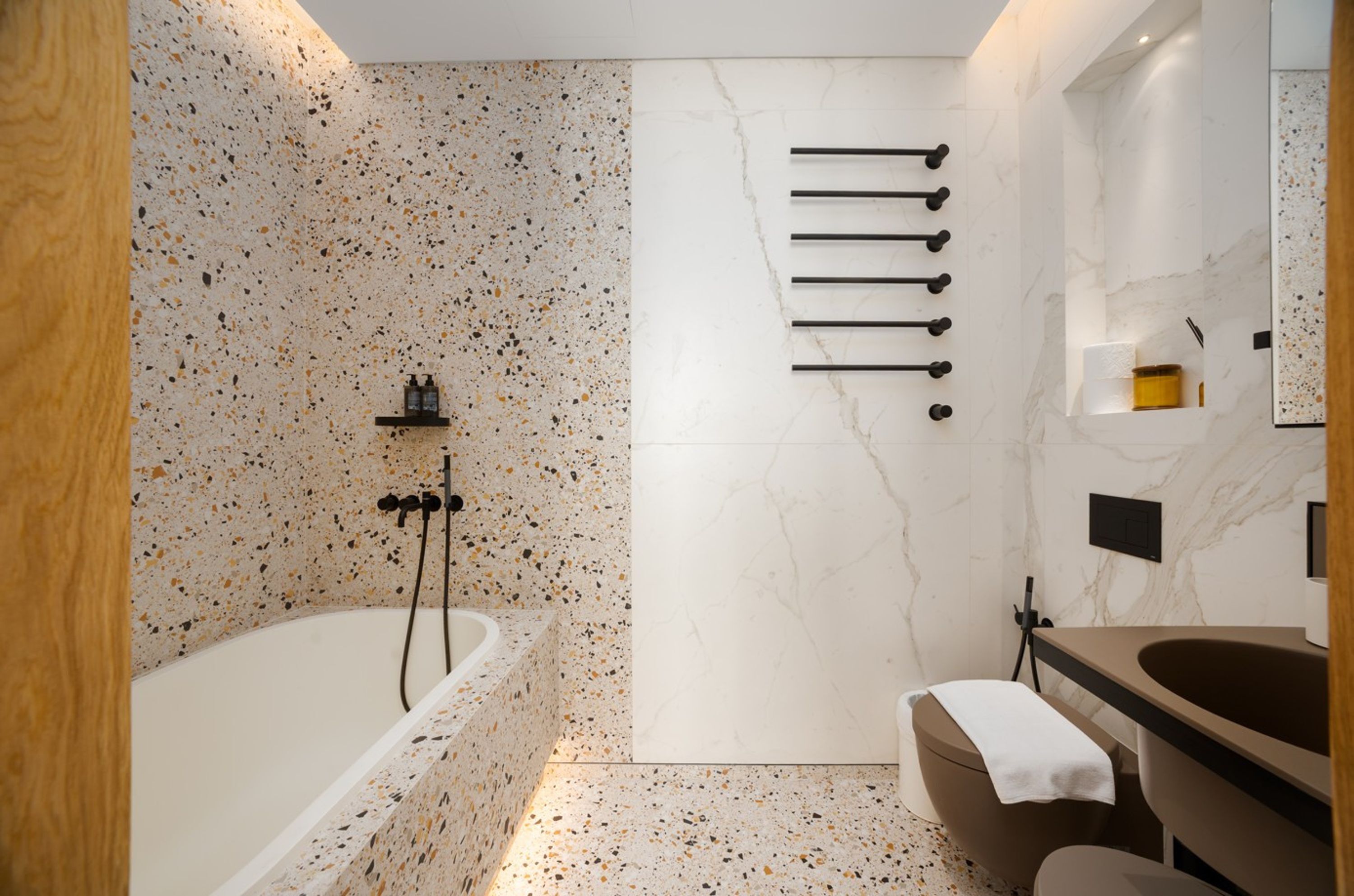 Ein modernes Badezimmer mit einer freistehenden Badewanne, einem Waschtisch mit Spiegel und einem Handtuchhalter.