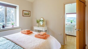 Una camera da letto con un letto, un comodino con uno specchio, una finestra che offre una vista e una porta che conduce in un'altra stanza.