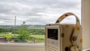Una finestra con vista su un paesaggio rurale, una borsa a pois e un piccolo dispositivo con schermo.