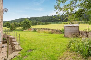 Ett grönområde med en stenmur, ett trähus och en satellantenn.