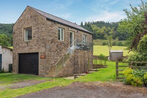 A stone building with a staircase leading to a second floor, a garage, and a fenced garden area. - 1 Bed in Chaigley (oc-c44973) (Aighton, Bailey and Chaigley)