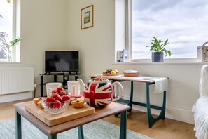 A cozy living room with a wooden table set for tea, a television, and a window with a view. - 1 Bed in Chaigley (oc-c44973) (Aighton, Bailey and Chaigley)