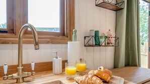 A kitchen with a wooden countertop, a gold faucet, a bottle of hand soap, a roll of paper towels, and two glasses of orange juice. - 1 Bed in Broxburn (oc-t44711) (Broxburn)