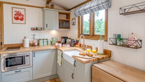 A kitchen with a wooden countertop, a sink, a window with curtains, and a shelf with kitchen items. - 1 Bed in Broxburn (oc-t44711) (Broxburn)