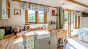 A kitchen with wooden beams, a window with curtains, a sink, and various kitchen appliances. - 1 Bed in Broxburn (oc-t44711) (Broxburn)