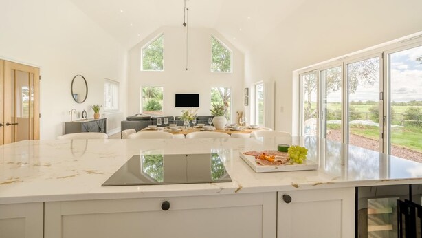 Una cocina amplia con una isla grande, un comedor con sofá y un televisor montado en la pared.