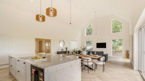 Una cocina amplia con una isla grande, un comedor con sillas y vistas al exterior.