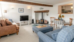 A living room with a television, sofa, ottoman, and a fireplace. - 2 Bed in Swimbridge (oc-p44771) (Swimbridge)